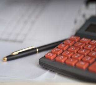 Imagen de un escritorio con una calculadora y un bolígrafo